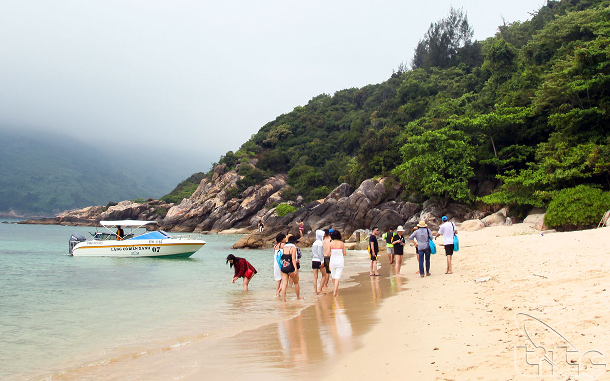Visitors take a walk on the beach in Ngoc Island